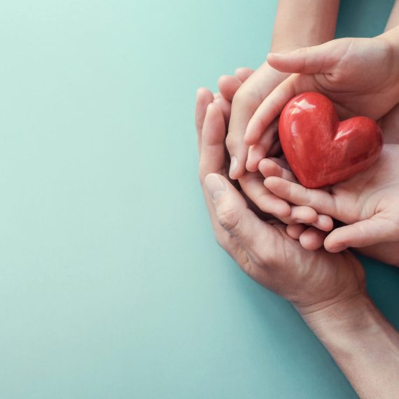 adult and child hands holding red heart on aqua background, heart health, donation, CSR concept, world heart day, world health day, family day